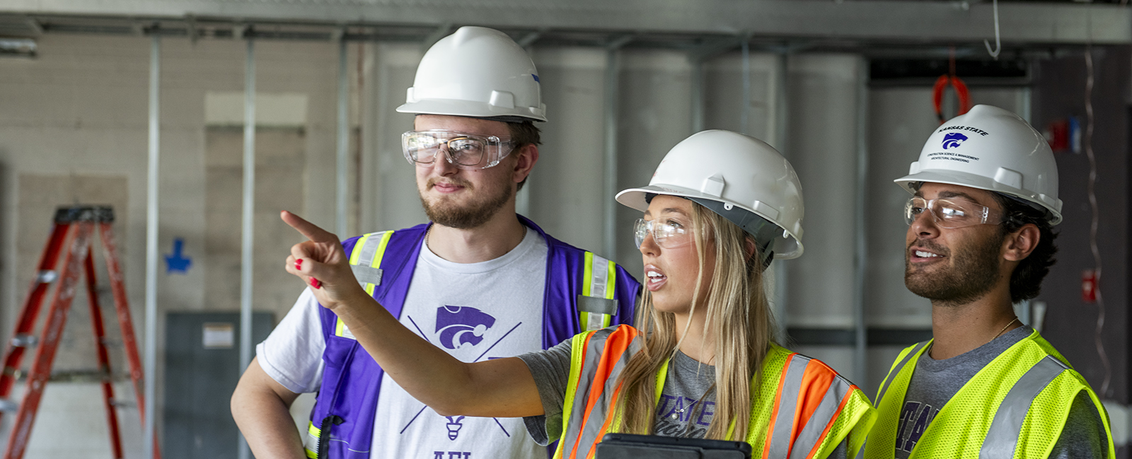 Three students stand in a construction site.